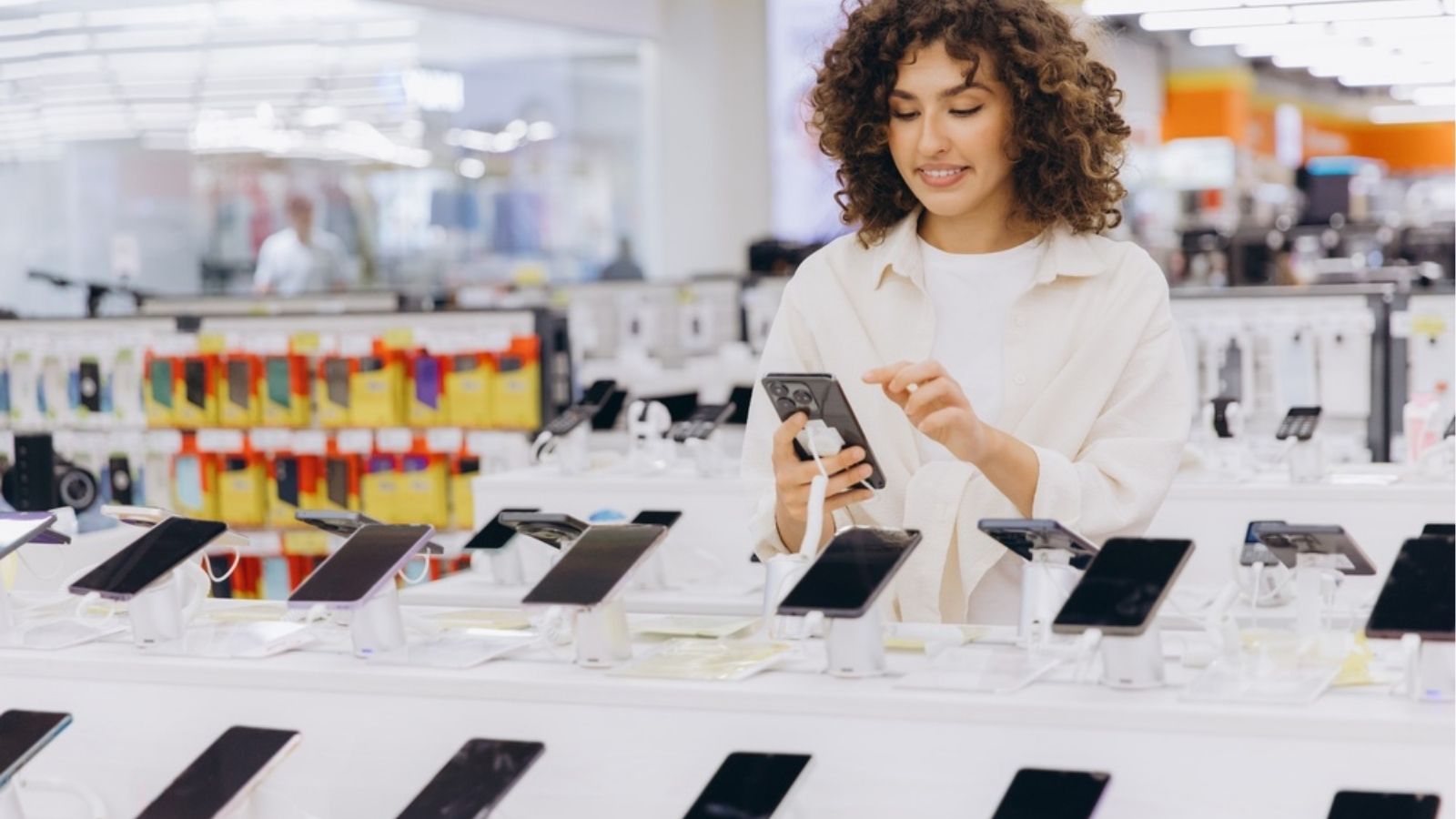 Klient oglądający smartfon w sklepie z elektroniką