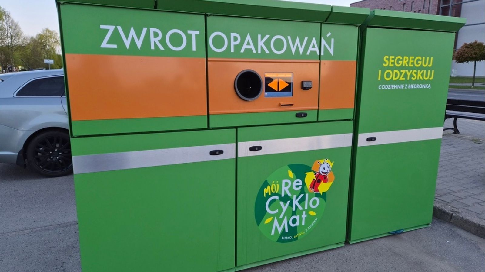 Klient trzyma wydrukowany voucher kaucyjny przy butelkomacie w sklepie Biedronka