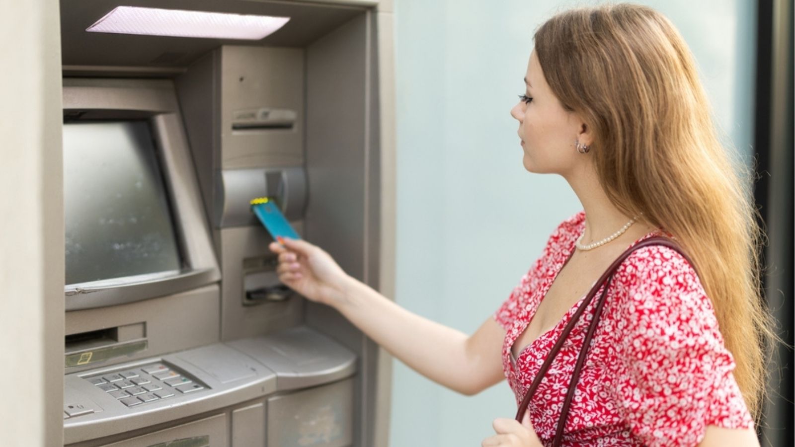 Klient wypłacający gotówkę z bankomatu objętego monitoringiem kamer.